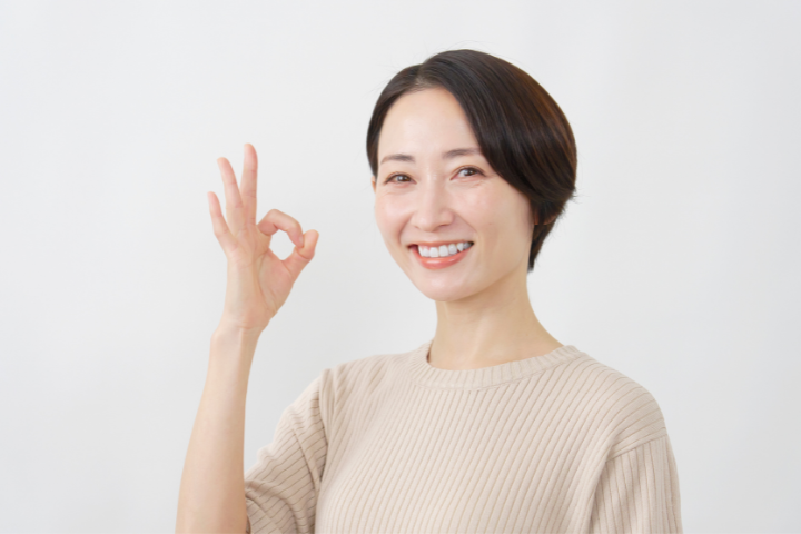 手でOKの形を作り笑顔の女性のイメージ