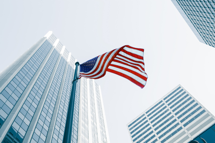ビル群の中にあるアメリカ国旗の画像